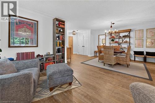 Open-concept living area featuring wood-finish flooring, built-in shelving, a chandelier, and double panel doors - 1237 North Shore Boulevard Unit# 405, Burlington, ON - Indoor Photo Showing Living Room
