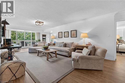 Spacious living area featuring wood-finish flooring, white walls, and crown molding - 1237 North Shore Boulevard Unit# 405, Burlington, ON - Indoor Photo Showing Living Room