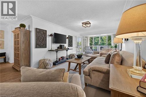 Living area featuring crown molding, neutral wall tones, and wood-finish flooring - 1237 North Shore Boulevard Unit# 405, Burlington, ON - Indoor Photo Showing Living Room