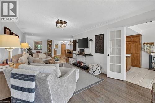 Open-concept living area featuring wood-finish flooring, white crown molding, and a modern flush-mount ceiling light fixture - 1237 North Shore Boulevard Unit# 405, Burlington, ON - Indoor Photo Showing Living Room