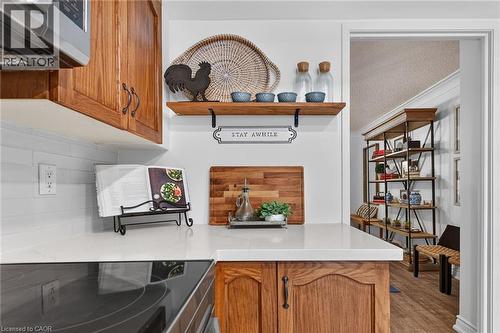 Kitchen counter with a smooth cooktop, white subway tile backsplash, wood-finish cabinetry, and solid surface countertop - 1237 North Shore Boulevard Unit# 405, Burlington, ON - Indoor