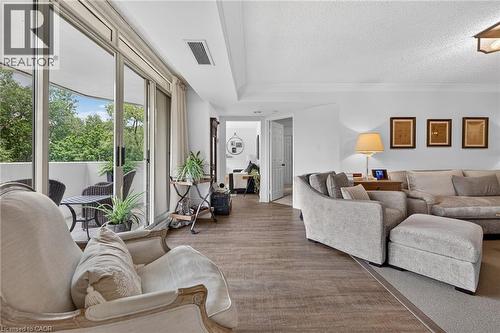 Spacious living area featuring wood-finish flooring extending to a private balcony - 1237 North Shore Boulevard Unit# 405, Burlington, ON - Indoor Photo Showing Living Room