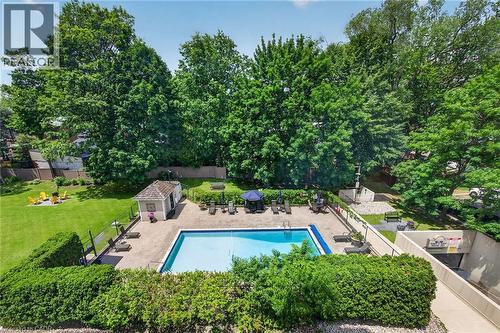 Outdoor swimming pool with surrounding paver patio and mature tree landscaping - 1237 North Shore Boulevard Unit# 405, Burlington, ON - Outdoor With In Ground Pool With Backyard