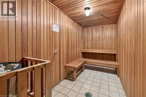 Wood-paneled sauna featuring tiered wooden benches, a built-in heater with protective railing, and square tile flooring - 1237 North Shore Boulevard Unit# 405, Burlington, ON - Indoor Photo Showing Other Room