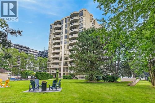 Expansive green lawn area featuring mature trees and a paved patio with seating - 1237 North Shore Boulevard Unit# 405, Burlington, ON - Outdoor With Balcony