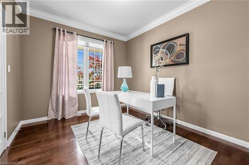 Interior space featuring rich wood-finish flooring, neutral-toned walls, a large window with grilles, and crown molding - 729 Boughton Crescent, Milton, ON 
