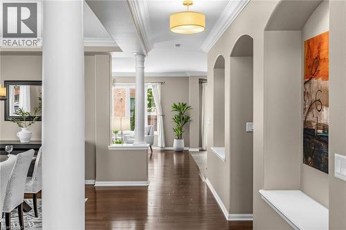 Hallway with wood-finish flooring, arched wall niches, crown molding, and a drum pendant light fixture - 729 Boughton Crescent, Milton, ON 