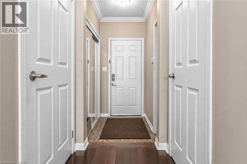 Entryway featuring wood-finish flooring, crown molding, and a paneled entry door with satin nickel hardware - 729 Boughton Crescent, Milton, ON 