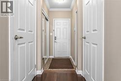 Entryway featuring wood-finish flooring, crown molding, and a paneled entry door with satin nickel hardware - 