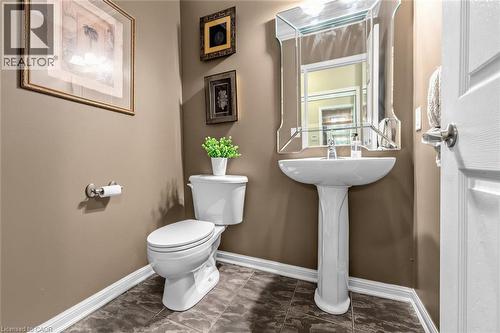 Pedestal sink with an ornate mirrored vanity, complemented by ceramic tile flooring and white baseboards - 729 Boughton Crescent, Milton, ON 