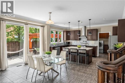 Open-concept living area featuring a kitchen with dark wood-finish cabinetry, a central island, and stainless steel appliances, including a range hood - 729 Boughton Crescent, Milton, ON 