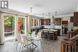 Open-concept living area featuring a kitchen with dark wood-finish cabinetry, a central island, and stainless steel appliances, including a range hood - 