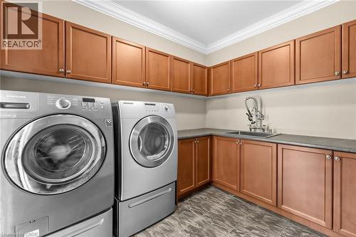 Dedicated laundry room featuring extensive cabinetry, a utility sink with a high-arc faucet, and durable tile flooring - 729 Boughton Crescent, Milton, ON 