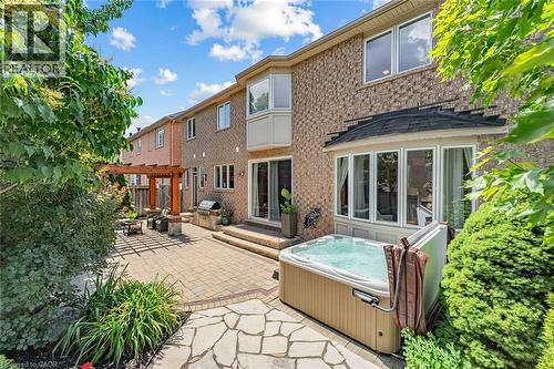 Brick exterior featuring a private hot tub, paver patio, stone patio, and a pergola-covered outdoor dining area - 729 Boughton Crescent, Milton, ON 
