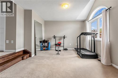 Carpeted bonus room featuring an arched window, a tray ceiling, and a built-in wall mirror - 729 Boughton Crescent, Milton, ON 
