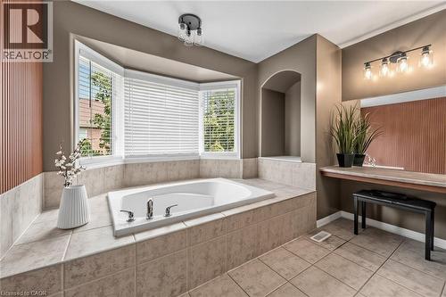 Bathroom featuring a built-in soaking tub with chrome fixtures, surrounded by tiled decking - 729 Boughton Crescent, Milton, ON 