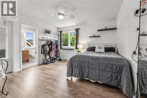 Bedroom featuring wood-finish flooring, a ceiling fan with integrated lighting, and a window with dark curtains - 729 Boughton Crescent, Milton, ON 