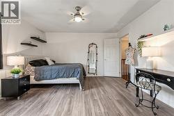Bedroom featuring wood-finish flooring, a ceiling fan, and white walls - 