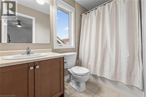 Bathroom featuring a vanity with a laminate countertop and wood-finish cabinetry, a built-in toilet, a window, and a tiled shower/tub combination - 729 Boughton Crescent, Milton, ON 