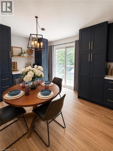 Kitchen area featuring extensive dark cabinetry, wood-finish flooring, a contemporary pendant light fixture, sliding glass doors, and open wood shelving - 355 East 36Th Street, Hamilton, ON 