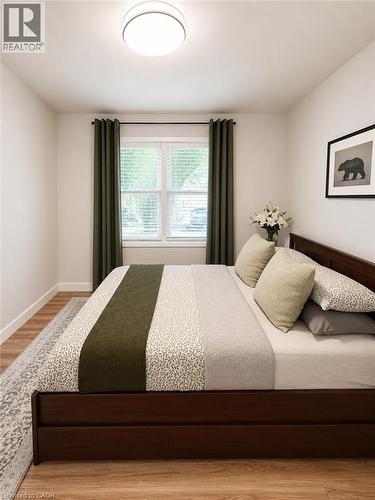 Light-filled room featuring wood-finish flooring, white walls, and a large window with white blinds - 355 East 36Th Street, Hamilton, ON 