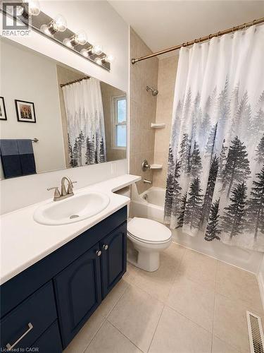 Full bathroom featuring a dark blue vanity, white countertop, and an integrated sink with brushed nickel faucet - 355 East 36Th Street, Hamilton, ON 