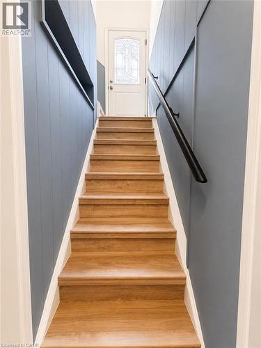 Staircase featuring wood-finish treads and risers, a matte black handrail, and beadboard wall paneling - 355 East 36Th Street, Hamilton, ON 