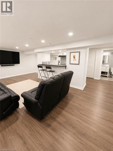Spacious entertainment area featuring wood-finish flooring, recessed lighting, and a built-in wet bar with a dark countertop and black faucet - 355 East 36Th Street, Hamilton, ON 