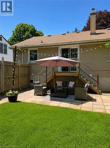 Rear exterior featuring a paver patio, wood deck with stairs, sliding glass doors, and a brick chimney - 355 East 36Th Street, Hamilton, ON 