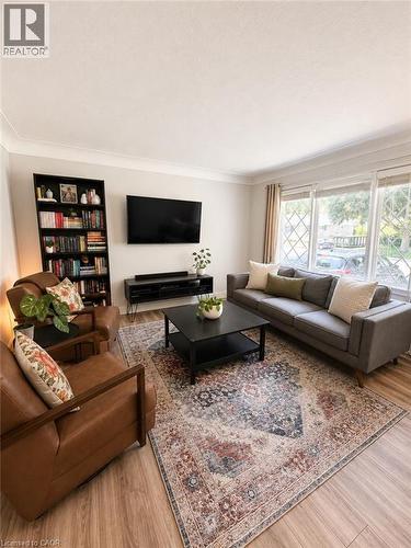 Living area featuring wood-finish flooring, crown molding, and large windows with decorative muntins - 355 East 36Th Street, Hamilton, ON 