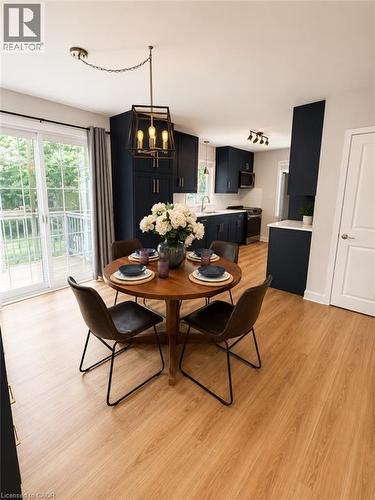 Dining area featuring wood-finish flooring, a modern geometric pendant light fixture, and sliding glass doors opening to an outdoor deck - 355 East 36Th Street, Hamilton, ON 