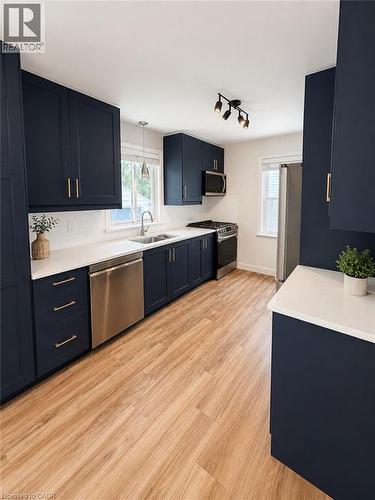 Kitchen featuring navy cabinetry, white countertops, wood-finish flooring, stainless steel appliances, and a white subway tile backsplash - 355 East 36Th Street, Hamilton, ON 