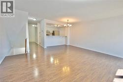 Spacious interior featuring wood-finish flooring, a contemporary chandelier, and an open-concept design - 