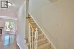 Carpeted staircase featuring a light wood handrail and classic white spindles - 
