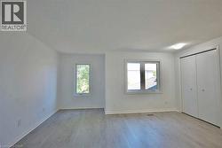 Room with wood-finish flooring, white walls, and bright overhead lighting - 