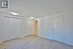 Room featuring light wood-finish flooring, white walls, and a textured white ceiling - 