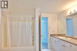 Full bathroom featuring a shower-over-tub combination, a spacious vanity with white cabinetry, a single basin sink, and a large wall-mounted mirror - 