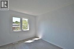 Light-filled room featuring a white-framed window, neutral wall tones, and wood-finish flooring - 