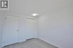 Room featuring a neutral color palette, wood-finish flooring, white baseboards, and a flush-mount ceiling light - 
