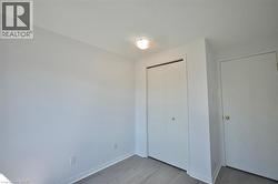 Room featuring a flush-mount ceiling light, light wood-finish flooring, white baseboards, and a bi-fold closet door with a brass knob - 