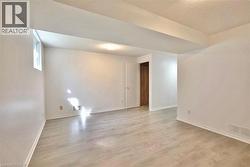 Spacious room featuring light wood-finish flooring, white baseboards, and a single window - 