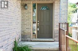 Inviting front entry featuring a paneled door with an arched transom window, a sidelight, and a concrete porch with metal railings - 