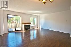 Spacious interior featuring wood-finish flooring, a contemporary fireplace with a wood mantle, and white baseboards - 