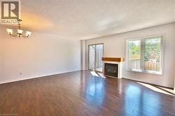 Spacious interior featuring wood-finish flooring, a built-in fireplace with a wood mantle, a multi-pane window, and a sliding glass door - 