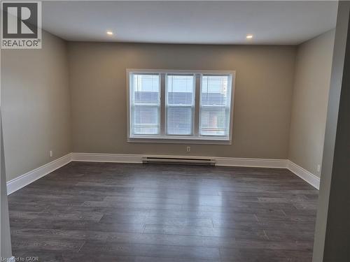 Spacious room featuring wood-finish flooring, recessed ceiling lighting, and a triple window off of kitchen - 181 King Street E Unit# 2, Kitchener, ON 