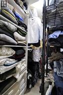 Custom closet system featuring built-in white shelving, integrated hanging rods, and wood-finish flooring - 