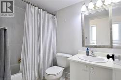 Bathroom featuring a white vanity with an integrated sink, a framed mirror, and a three-light fixture - 