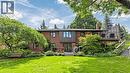 Expansive backyard featuring a manicured lawn, multi-level decking, mature trees, a brick facade, and a built-in bench - 438 Lexington Road, Waterloo, ON 