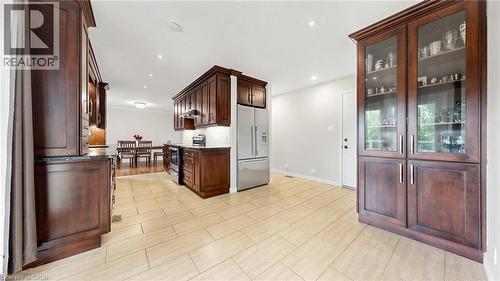 Open-concept kitchen with wood-finish cabinetry, stainless steel appliances, and light-toned tile flooring - 438 Lexington Road, Waterloo, ON 