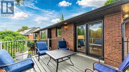 Exterior deck featuring composite decking, black metal railings, brick facade, and sliding glass doors - 438 Lexington Road, Waterloo, ON 